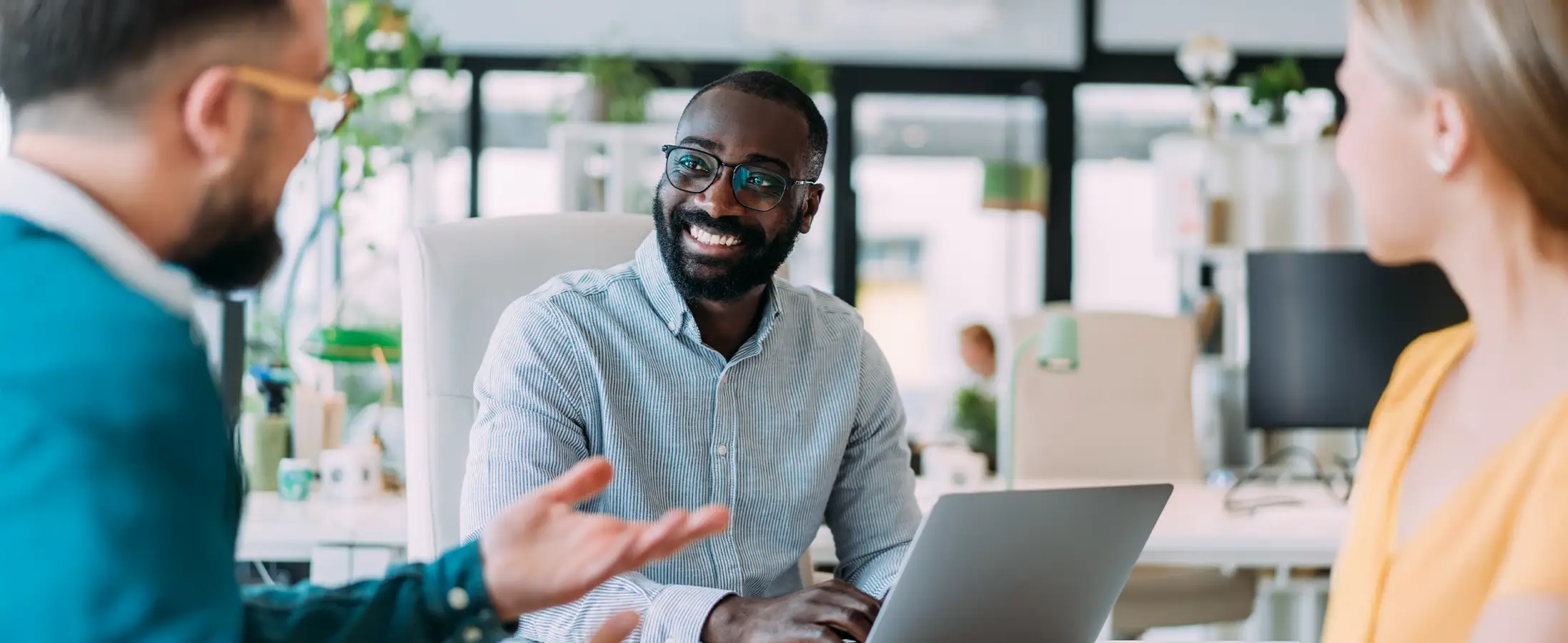 A man works on his computer while smiling at his coworkers in the office